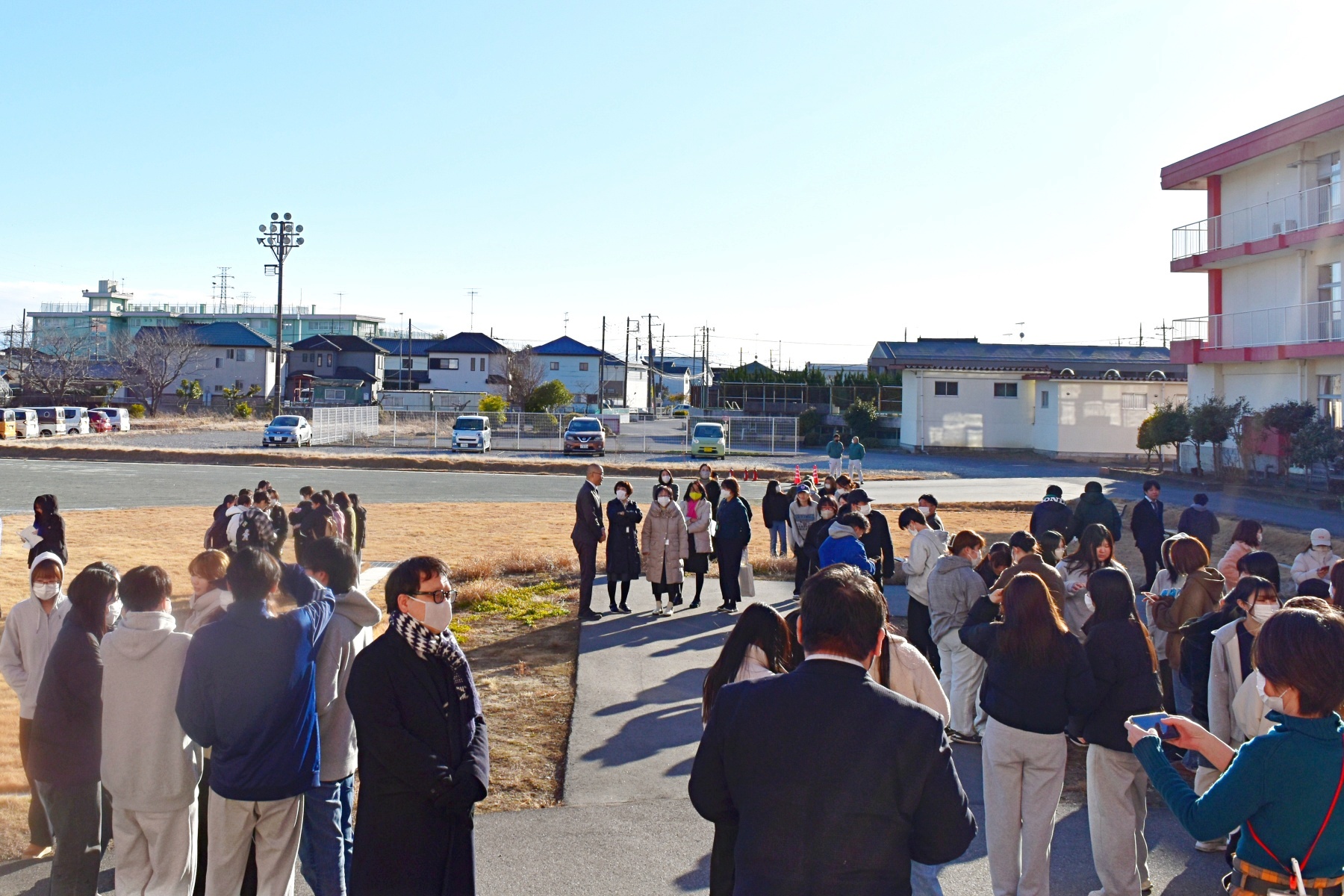 消防訓練後、グラウンドに避難・集合している学生と教職員の様子