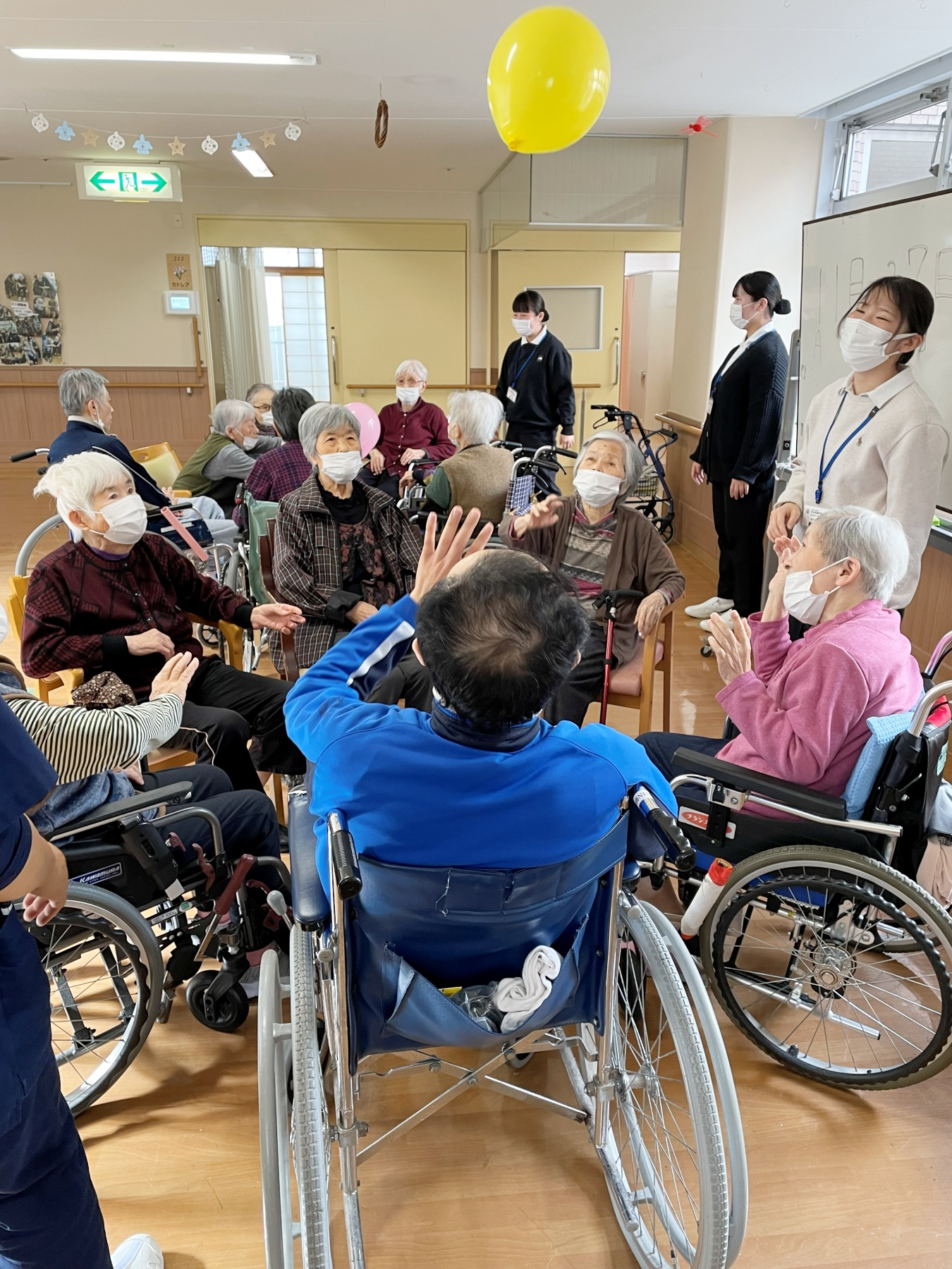 風船を使ったボールおくりゲームを楽しむ高齢者と学生の様子